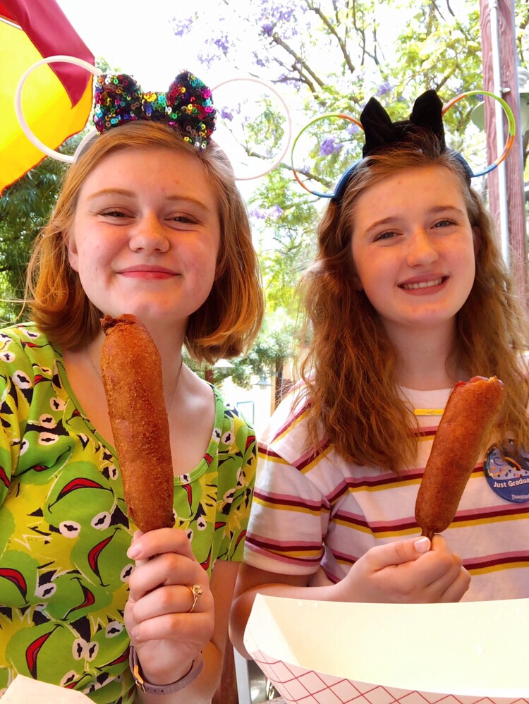 Hannah and Meg proudly showing off their corn dogs from Corn Dog Castle 